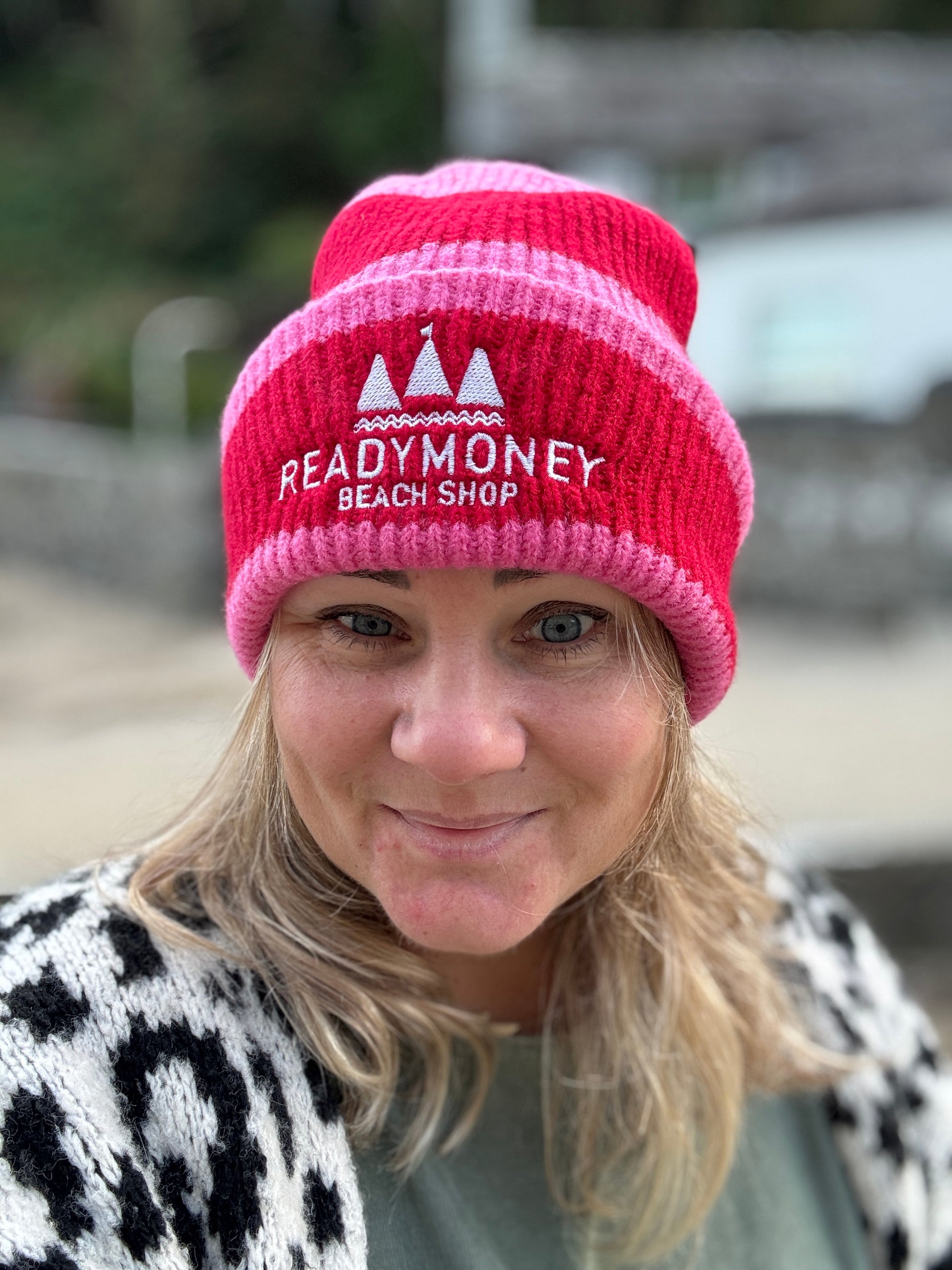 Readymoney Beach Shop beanie in pink and red—ribbed knit winter hat with coastal logo, styled for seaside outdoor adventures