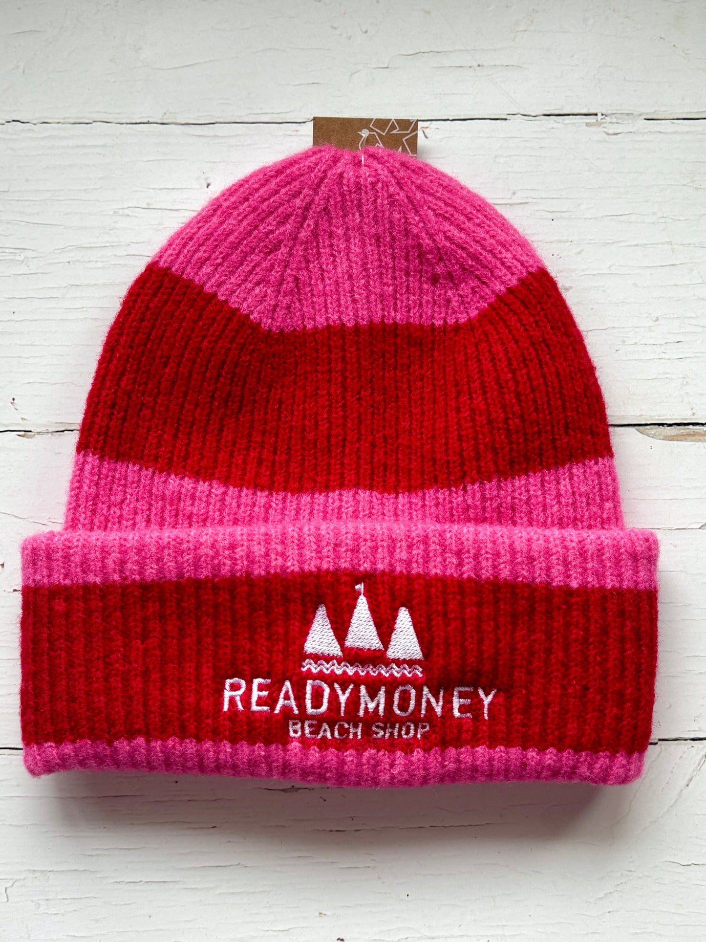 Readymoney Beach Shop beanie in red and pink—ribbed knit coastal hat with bold stripes and embroidered seaside logo