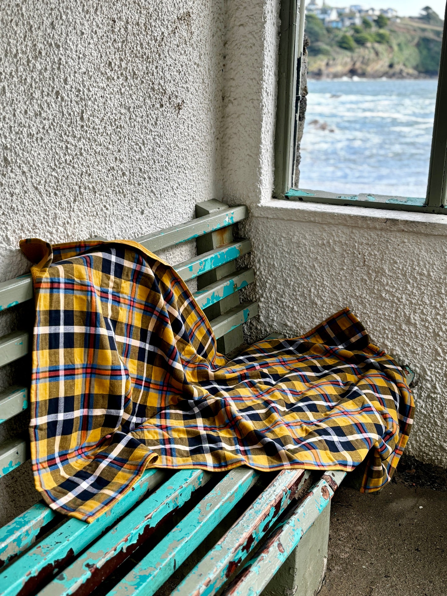 cozy yellow tartan cotton beach blanket draped on a bench overlooking the sea ersatile oversized throw for outdoor comfort
