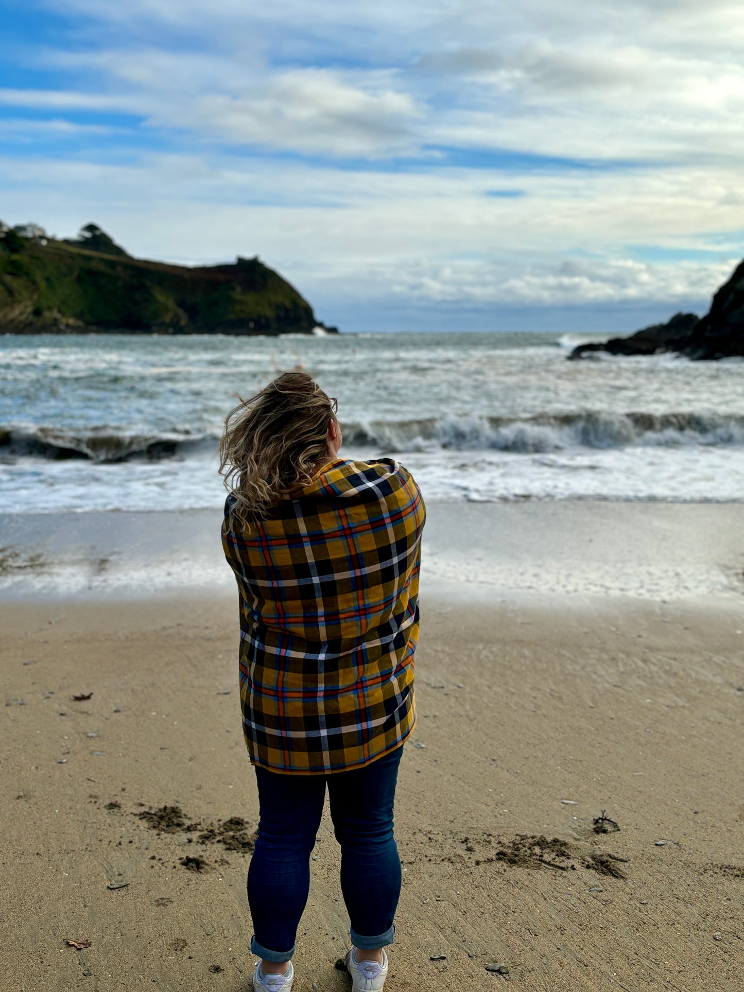 warm yellow tartan cotton beach towel/blanket wrapped around a woman on a scenic coastal beach stylish travel accessory