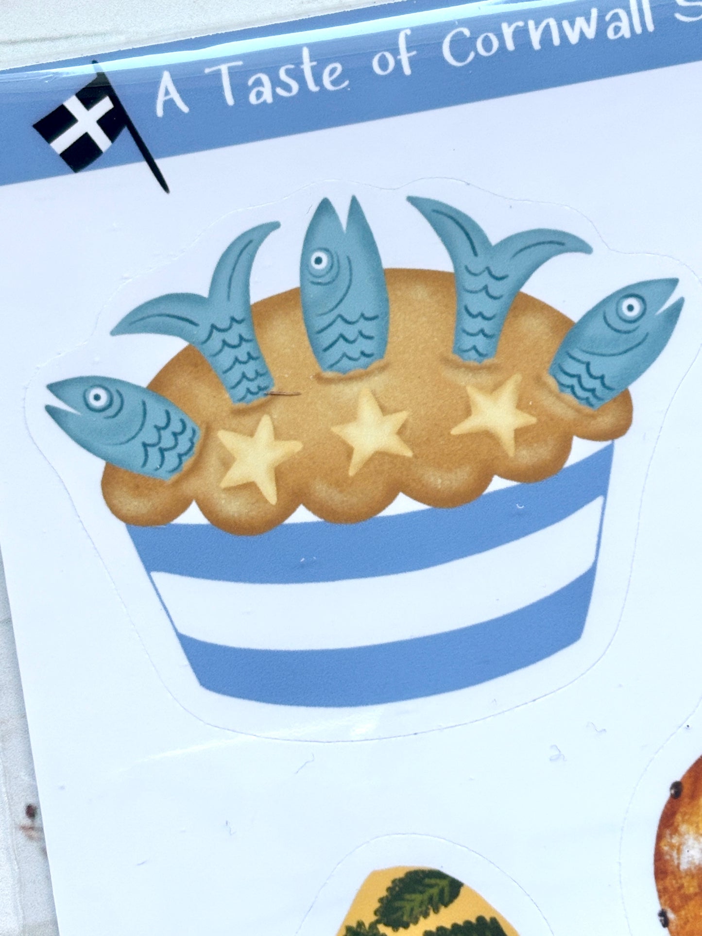 stargazy pie sticker closeup, Cornish traditional fish pie illustration with blue fish heads, pastry stars