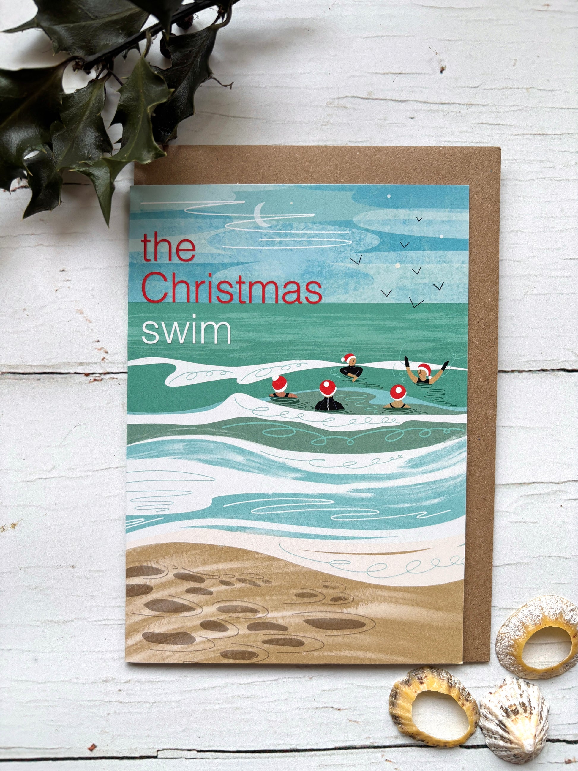 “The Christmas Swim” greeting card with swimmers in Santa hats in the sea, festive seaside holiday illustration
