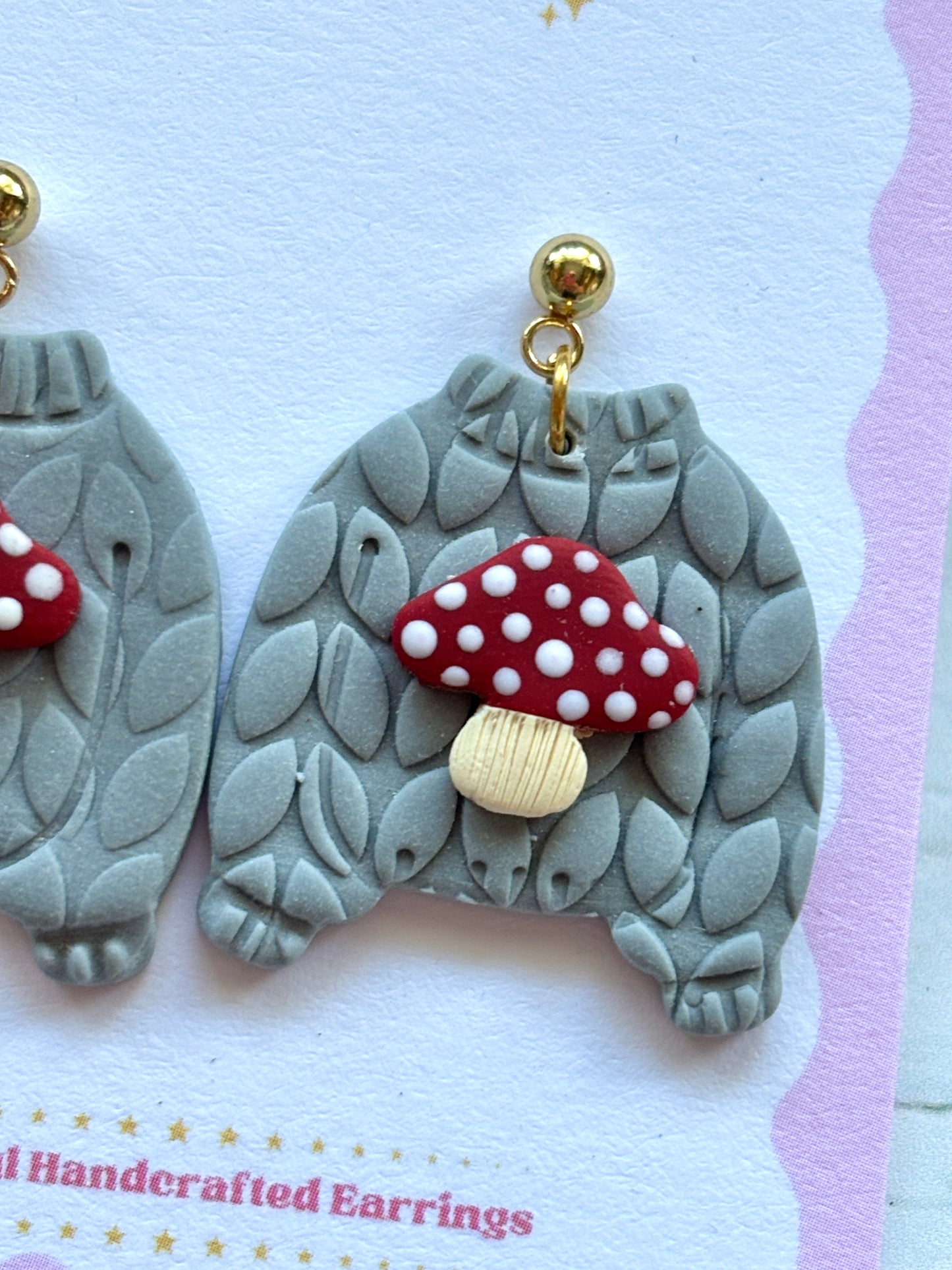 closeup shot of toadstool jumper earrings – cozy gray sweater studs with red mushroom detail, whimsical handmade fall accessory