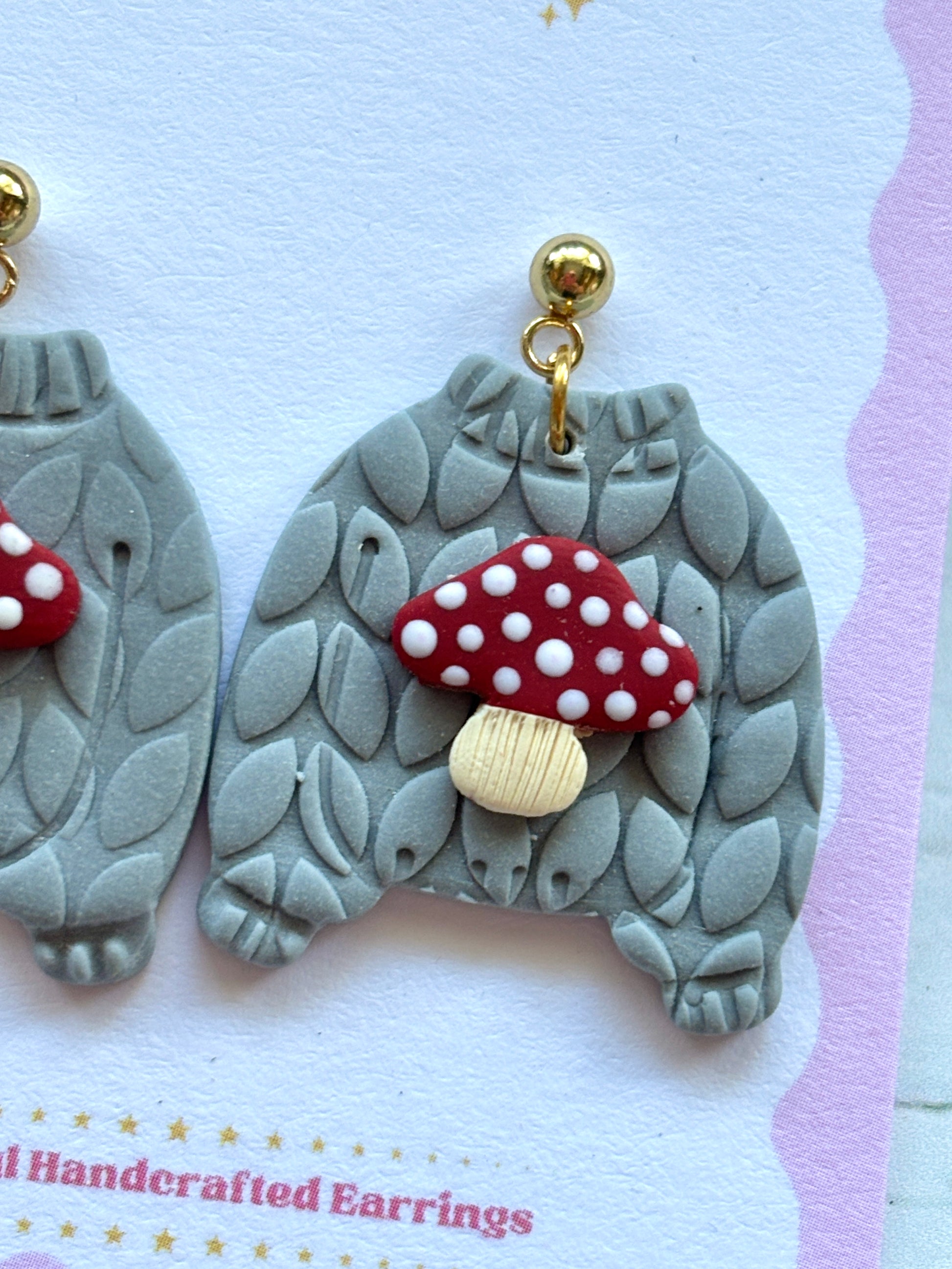 closeup shot of toadstool jumper earrings – cozy gray sweater studs with red mushroom detail, whimsical handmade fall accessory
