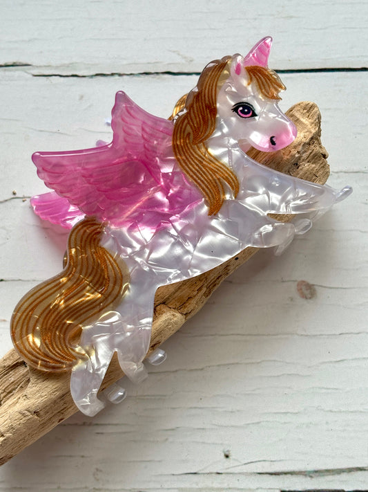 marbled pearlescent unicorn with pink wings and gold mane/tail hair claw clip funky Pegasus novelty accessory on driftwood