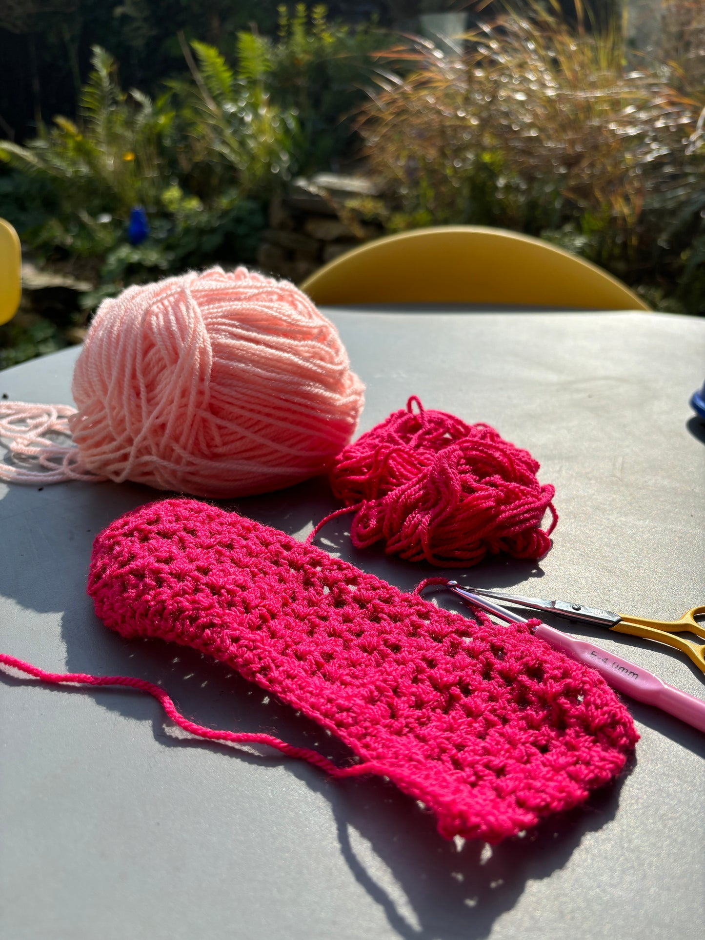crocheting-in-progress scene with bright pink yarn and a partially made washable soap saver bag handmade eco-friendly zero-waste craft supplies