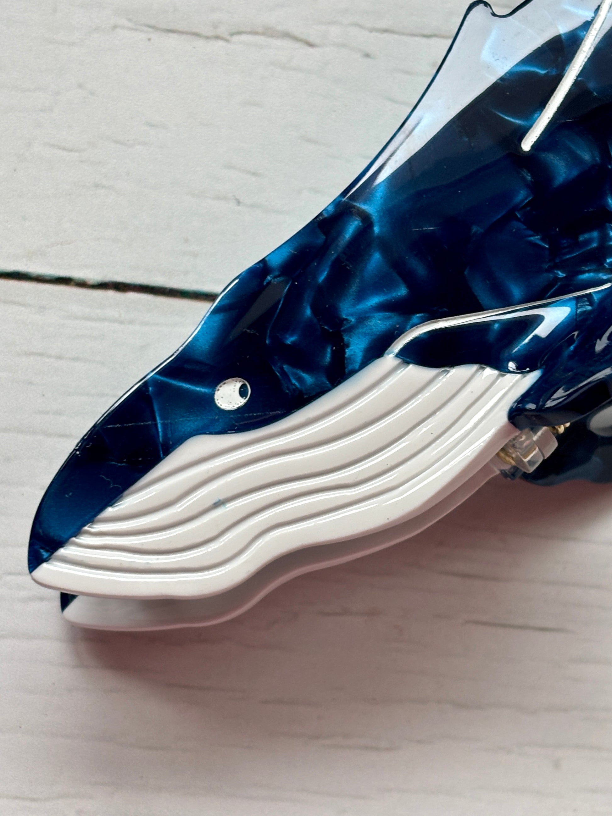 closeup shot of whale hair claw—deep blue marbled clip with white accents and ocean-inspired shape for coastal styling