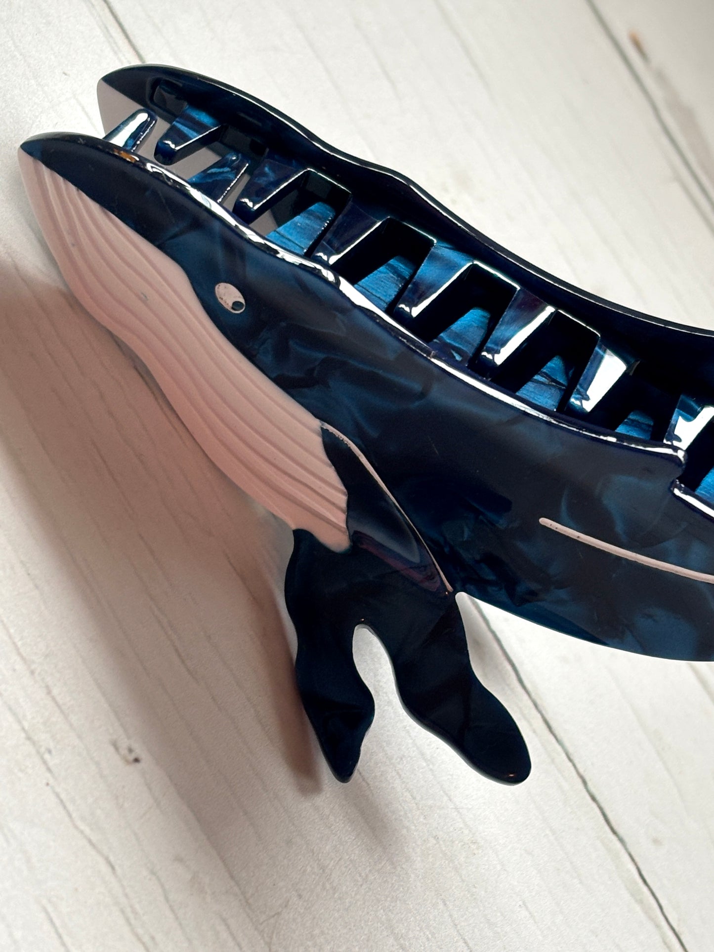 closeup shot of whale hair claw—dark blue clip with white accents, marine-inspired shape, and strong grip for coastal styling