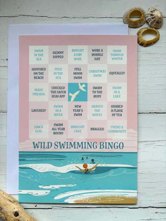 Wild Swimming Bingo greetings card outdoor water activity game with a beach illustration and pink grid coastal themed greeting card