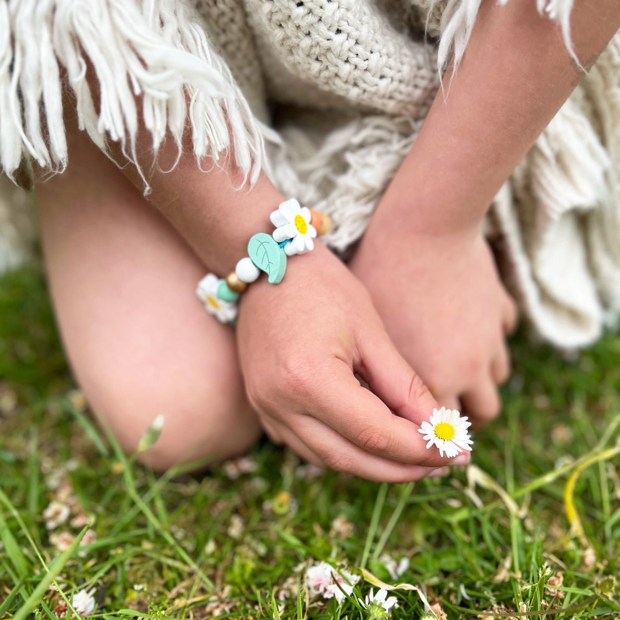 closeup shot of daisy flower wooden bead bracelet kids DIY jewelry accessory nature theme, boho aesthetic, summer wear