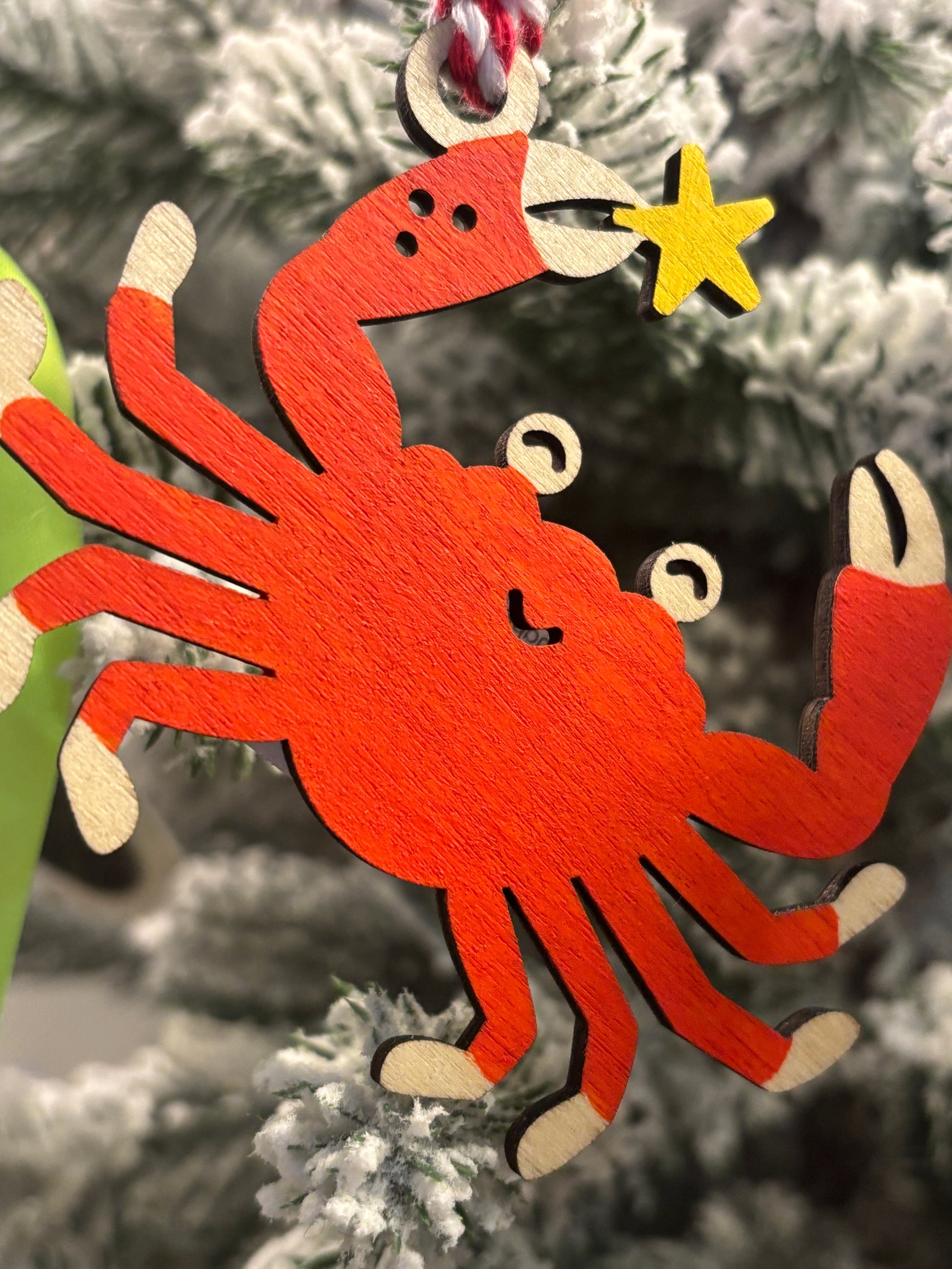 closeup shot of hand-painted wooden crab ornament holding starfish, bright orange beach-themed Christmas tree hanging decoration