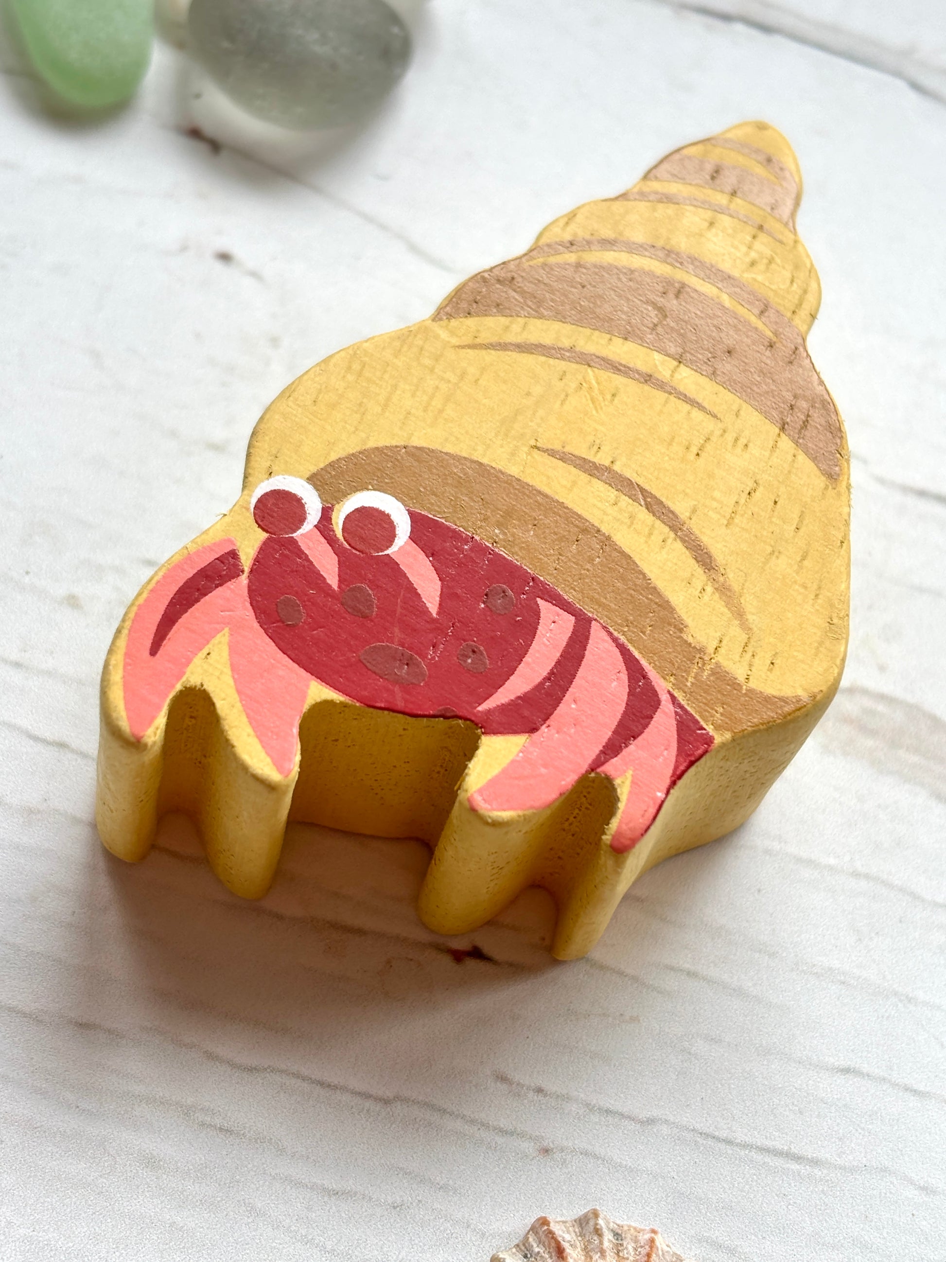 closeup shot of wooden hermit crab toy with spiral shell, hand-painted beach decor for coastal-themed play