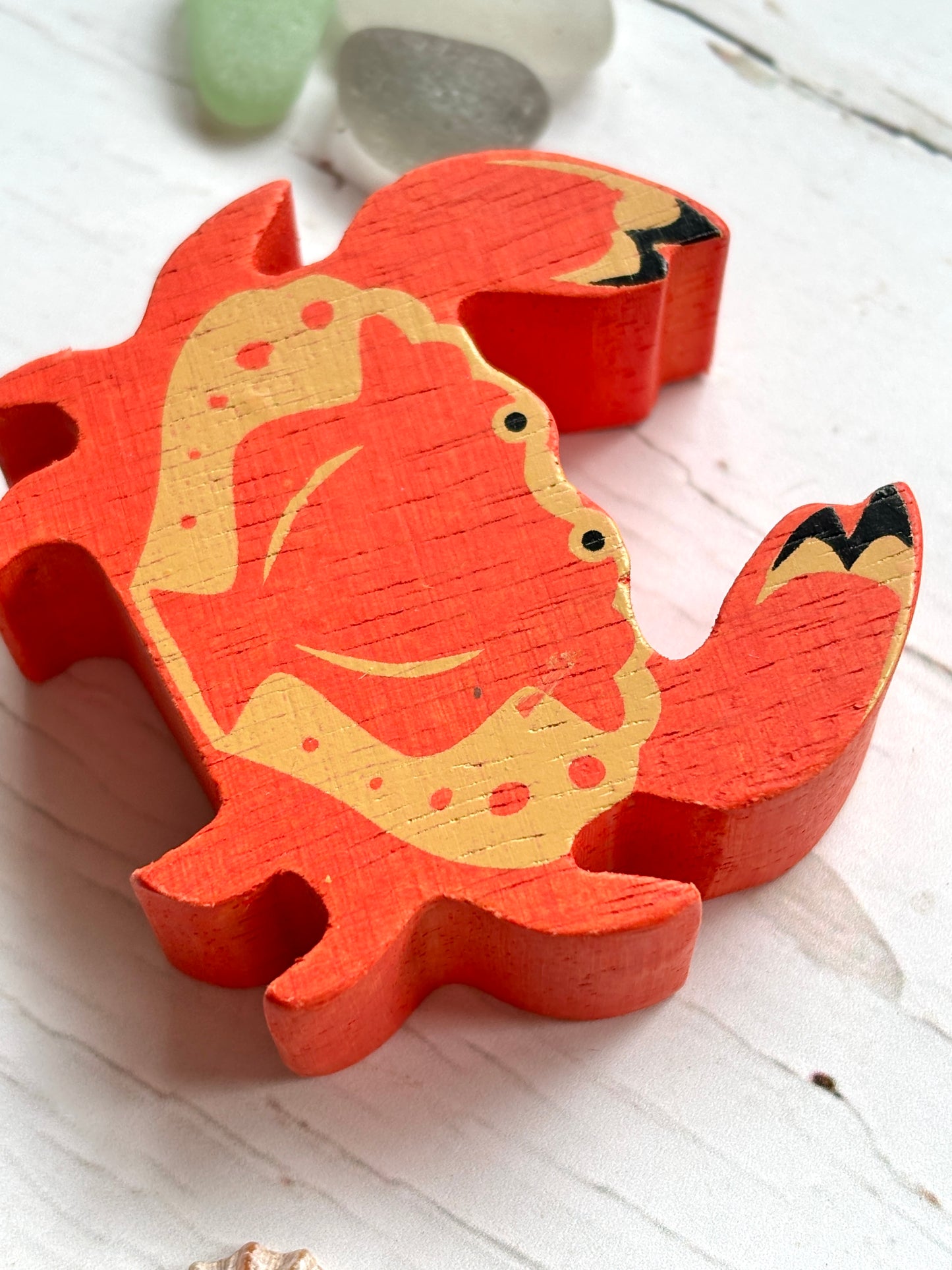 closeup shot of red-orange wooden crab toy with painted claws, beach-themed coastal decor for ocean lovers