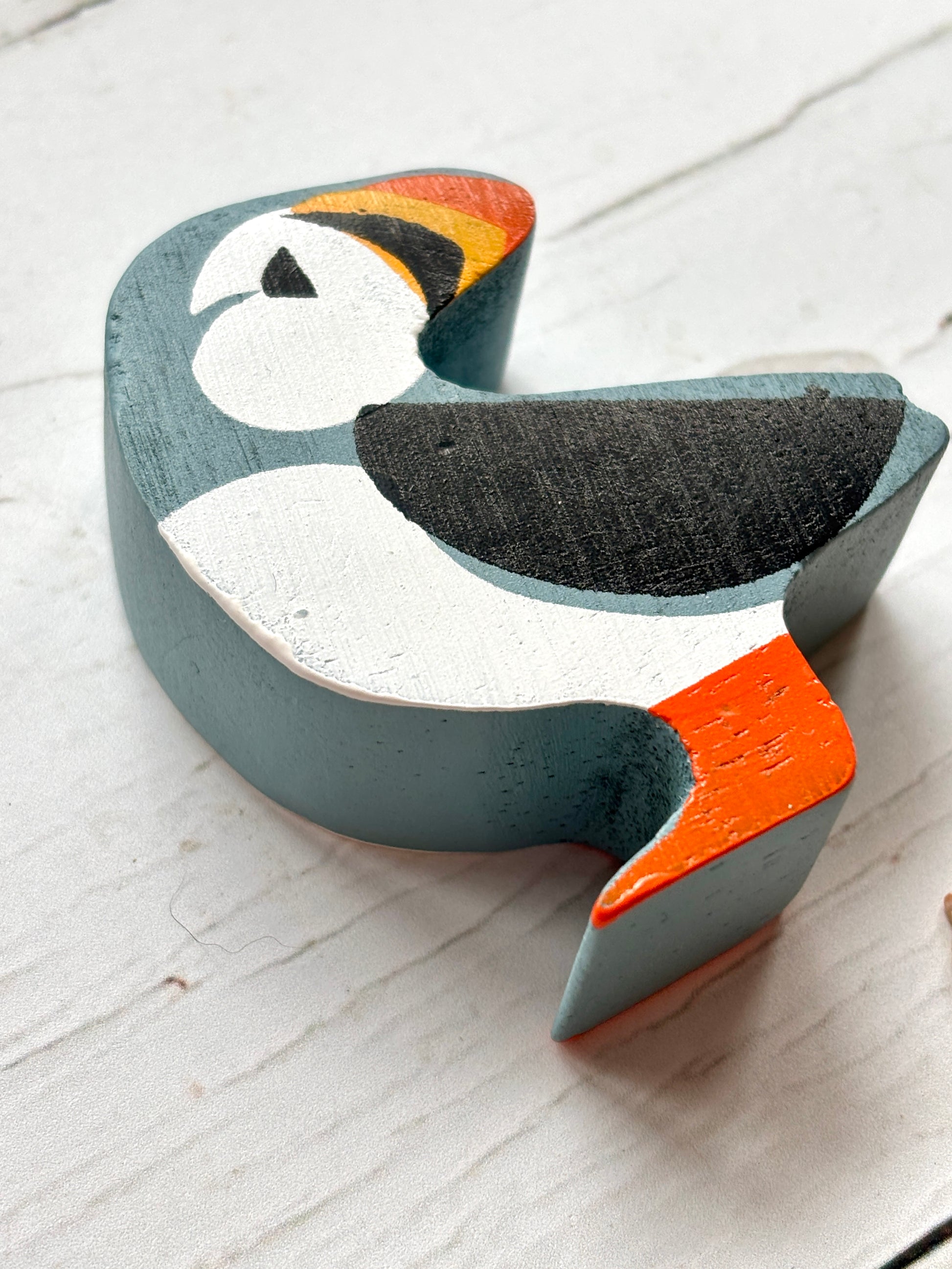 closeup shot of wooden puffin toy with bright beak and feet, hand-painted coastal bird decor for beach lovers