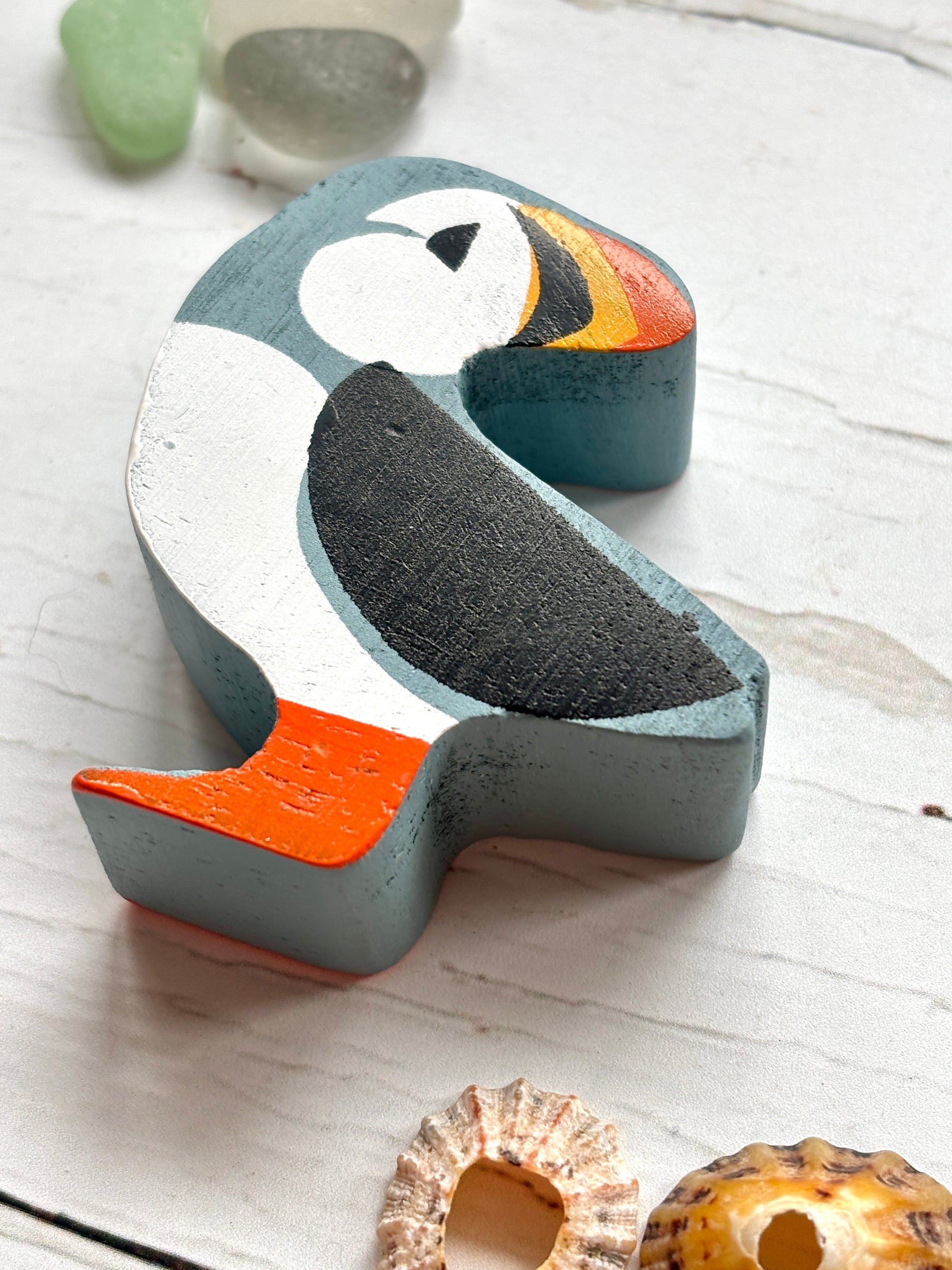 closeup shot of wooden puffin toy with bright beak and feet, hand-painted coastal bird decor for beach lovers