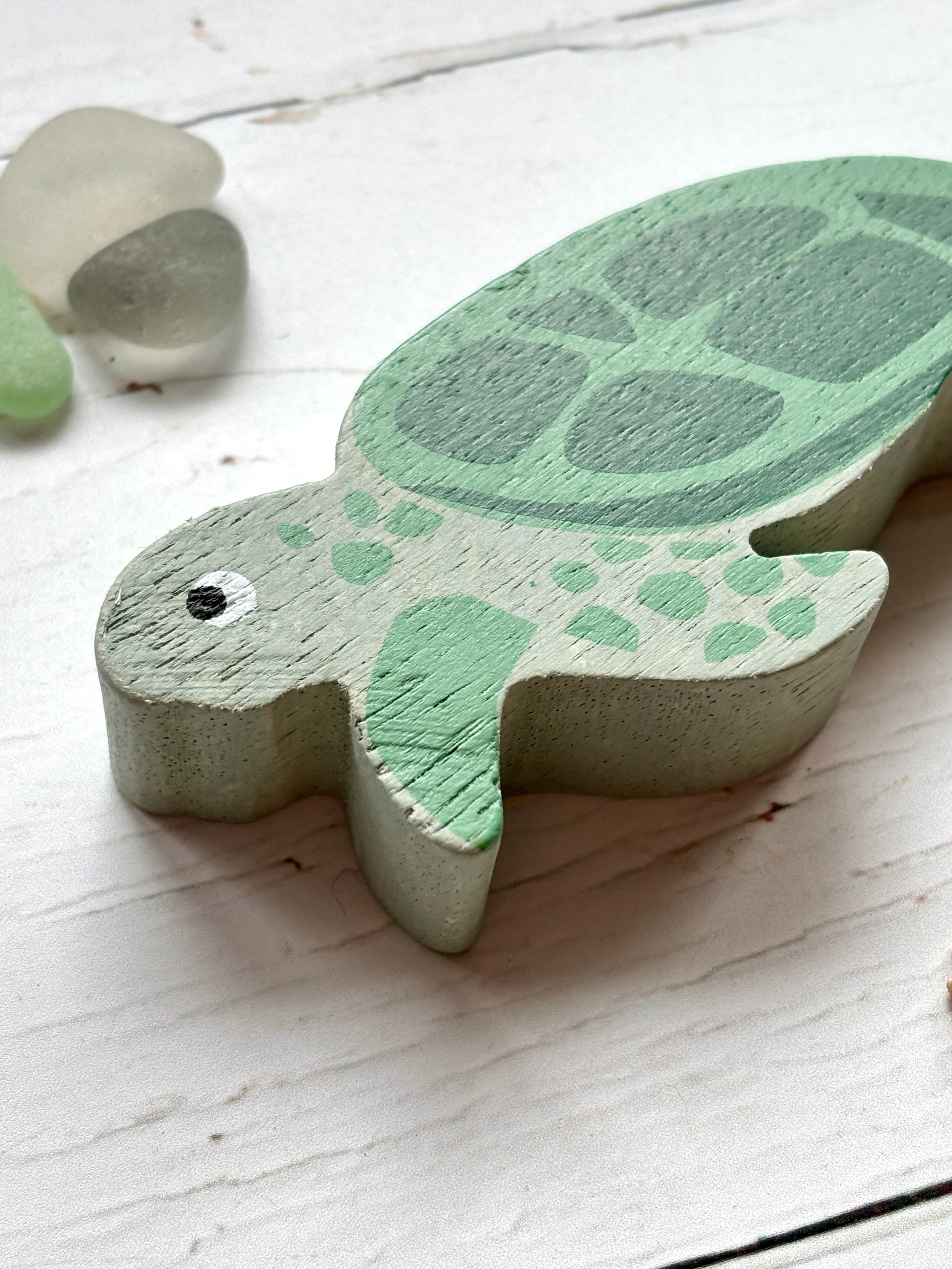 closeup shot of wooden sea turtle head with lifelike eye and green shell, hand-painted coastal animal toy