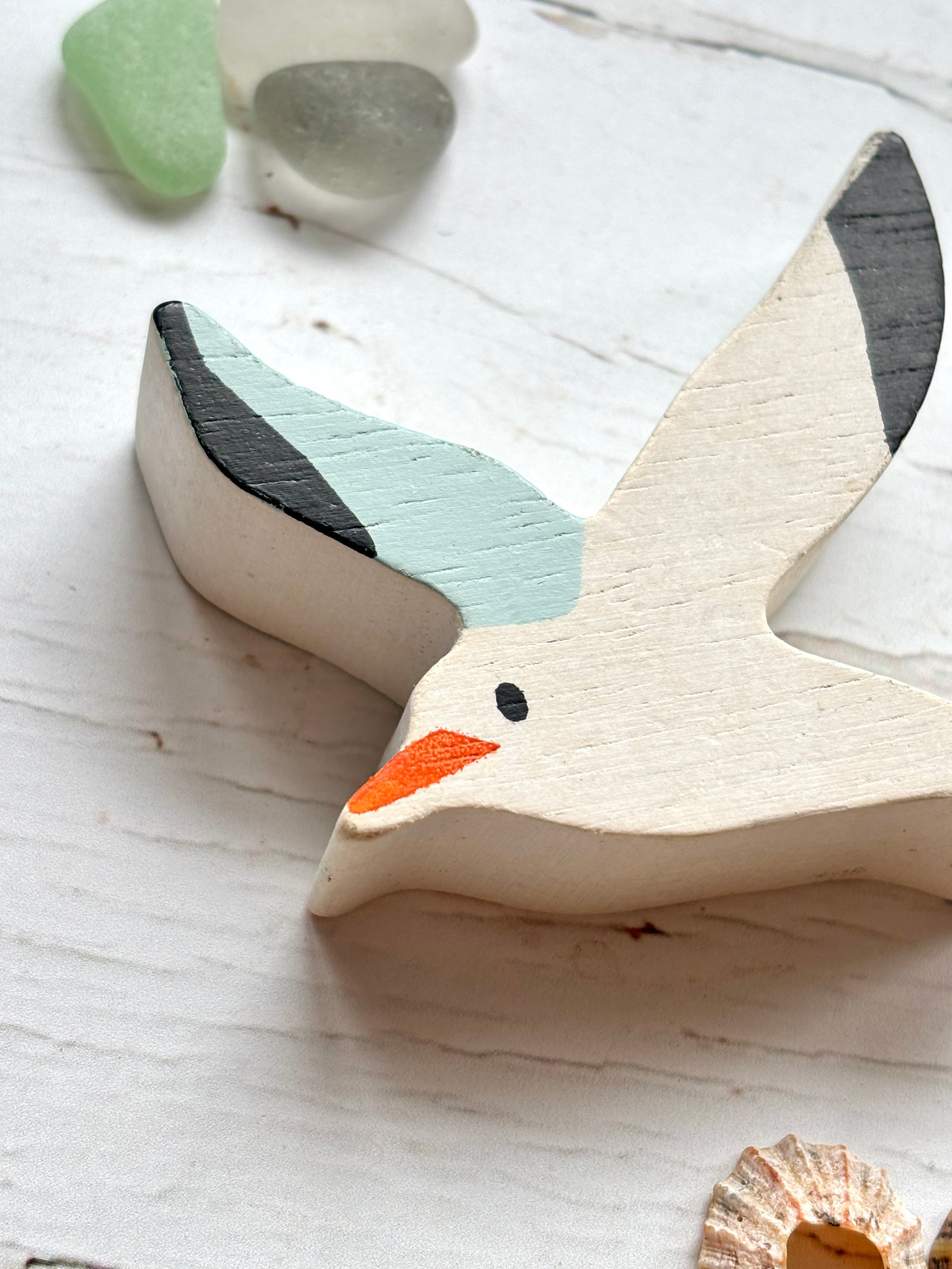 closeup shot of wooden seagull head with painted beak and eye, hand-crafted coastal bird decor for beach lovers