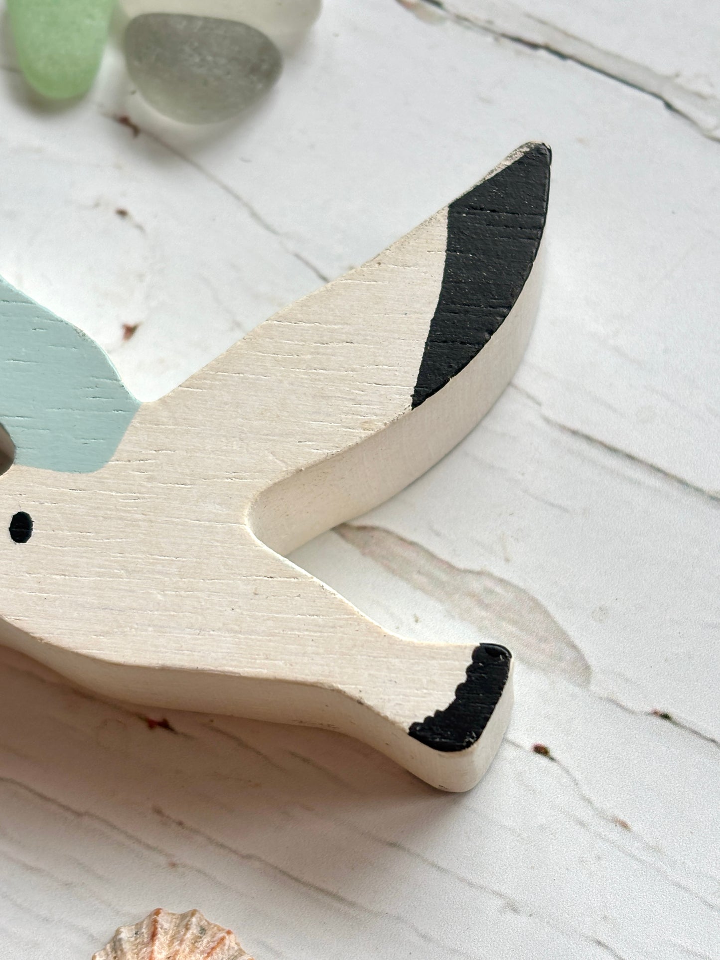 closeup shot of wooden seagull head with painted eye and wingtip, handcrafted coastal bird toy for beach-themed decor