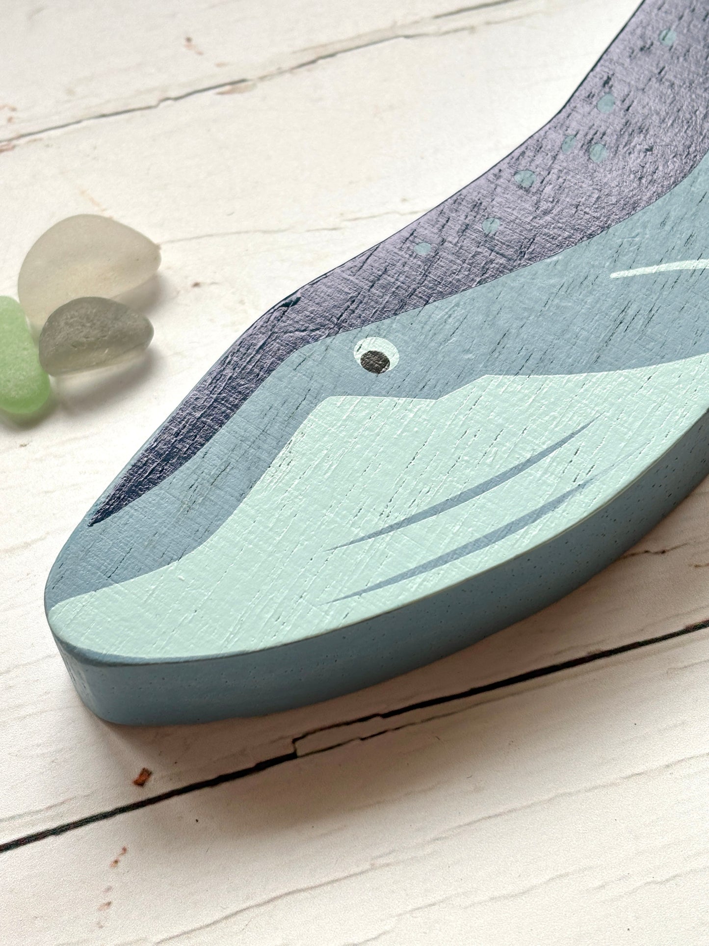 closeup shot of painted wooden whale head with blue tones, handcrafted coastal toy for nautical-themed decor