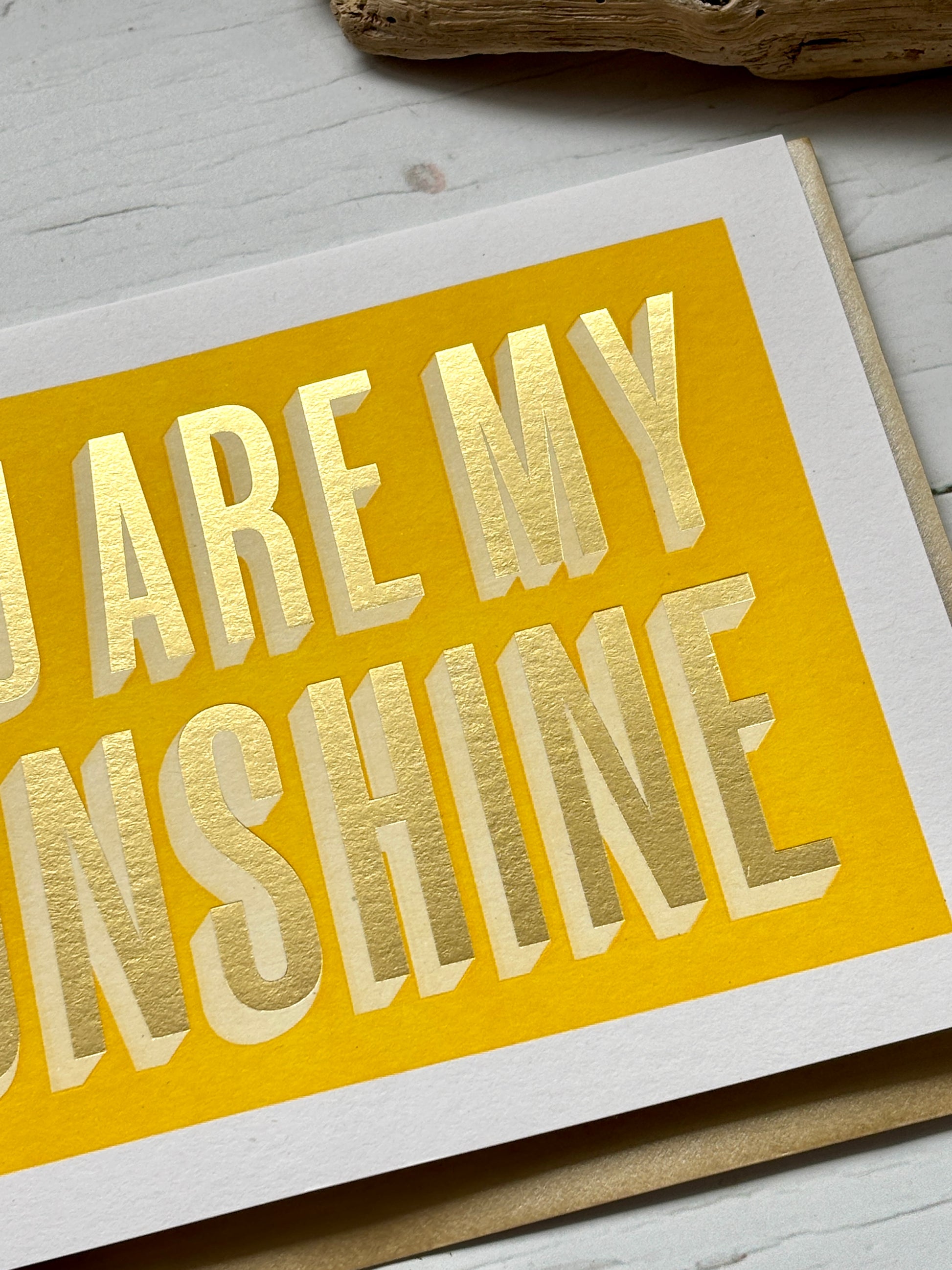 closeup shot of sunshine card with gold foil text on bold yellow, perfect for joyful gifting, beachy vibes, and heartfelt notes