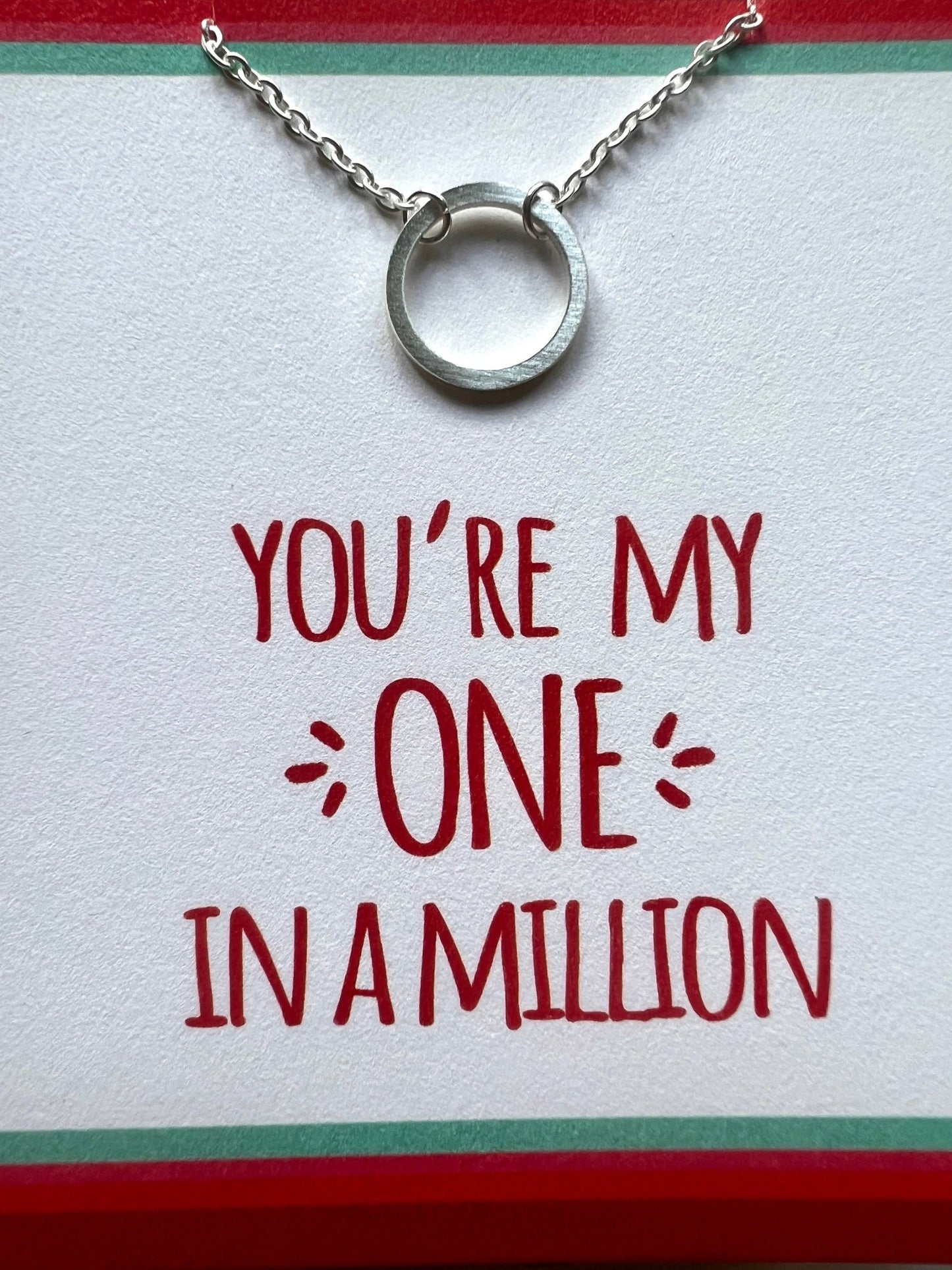 closeup shot of silver necklace on “One in a Million” card, romantic gift set with bold red and green border design
