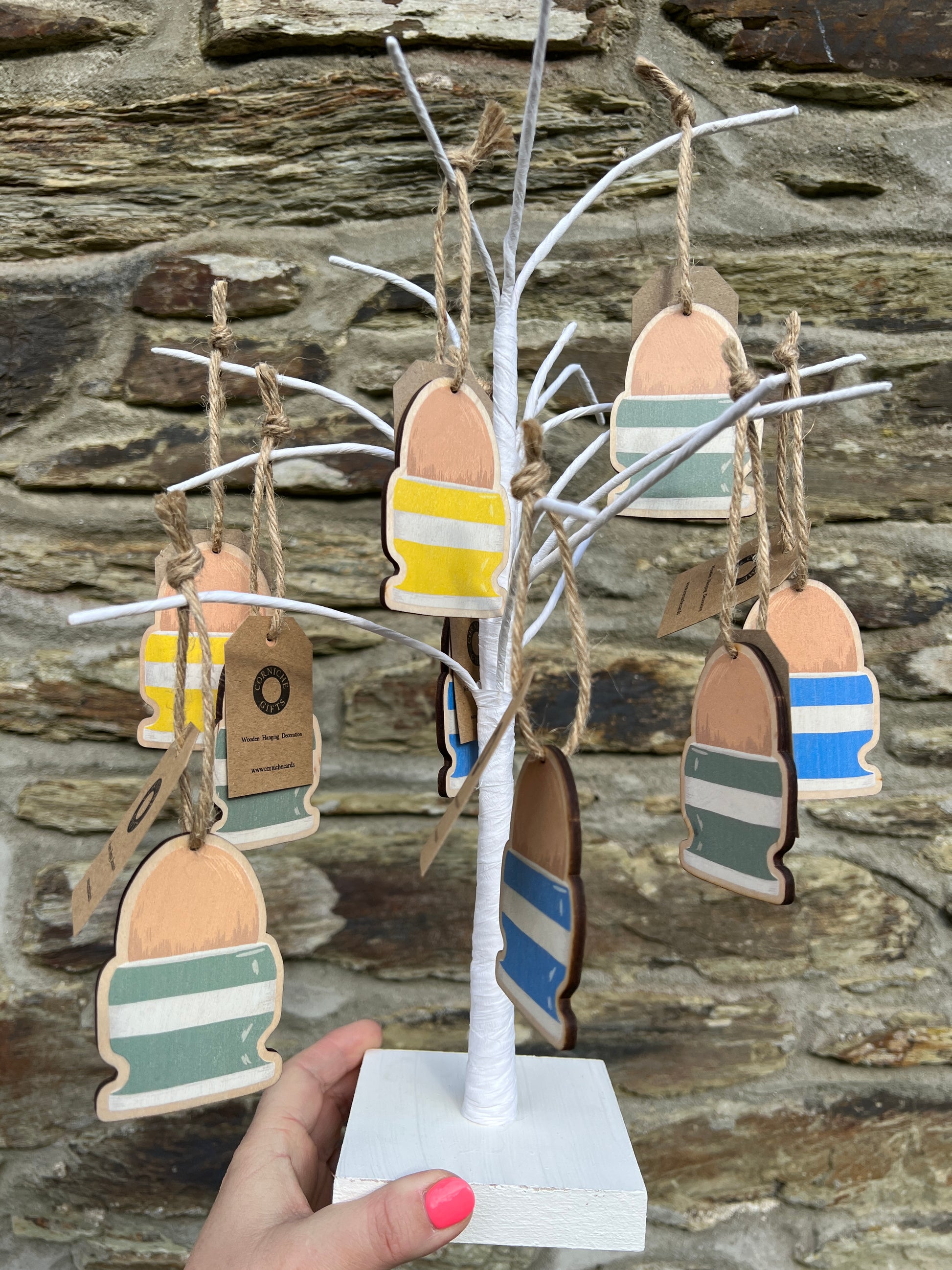 3 wooden eggcup easter decorations hanging on.a white twig tree