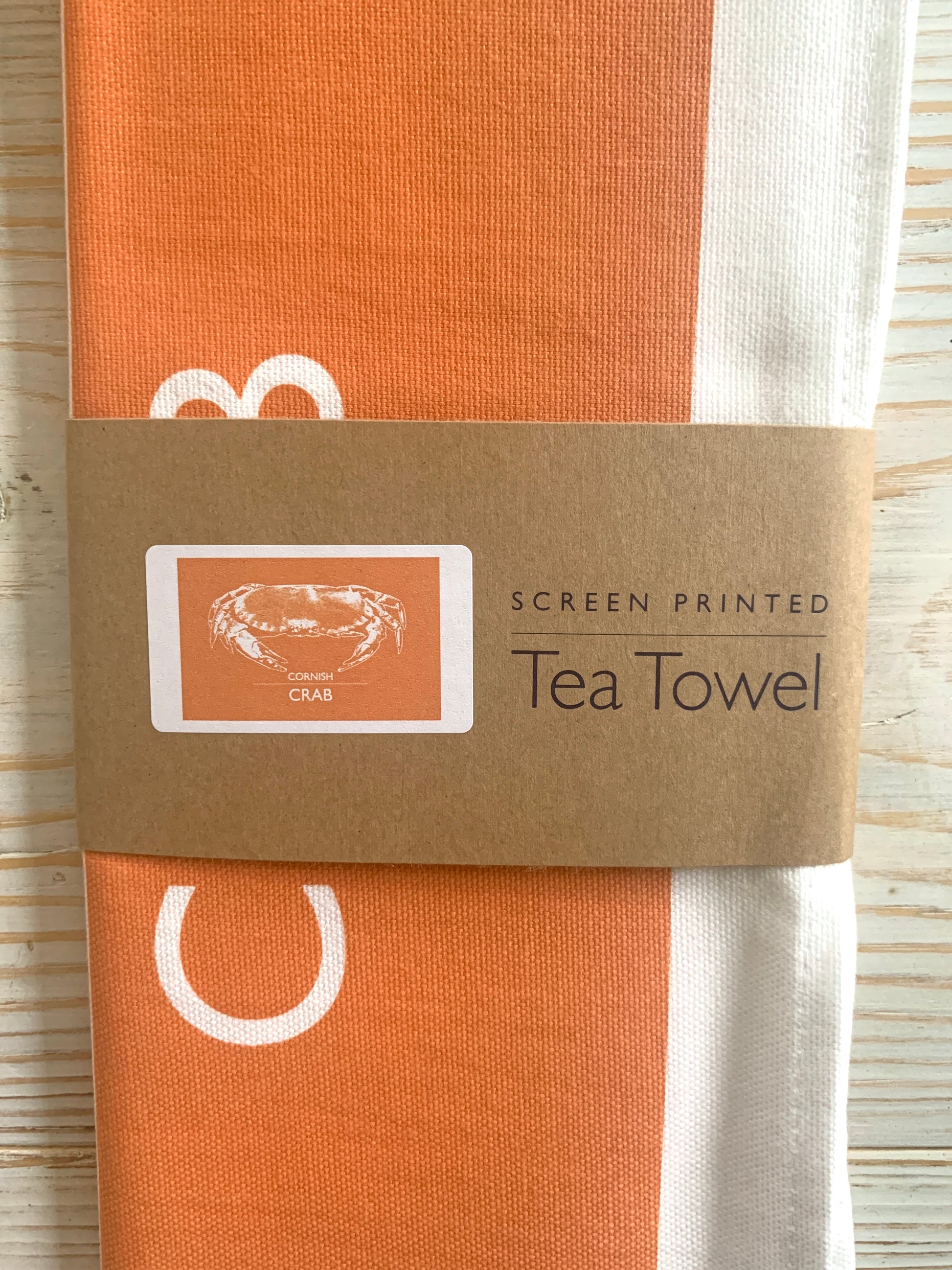 An orange tea towel with a crab design