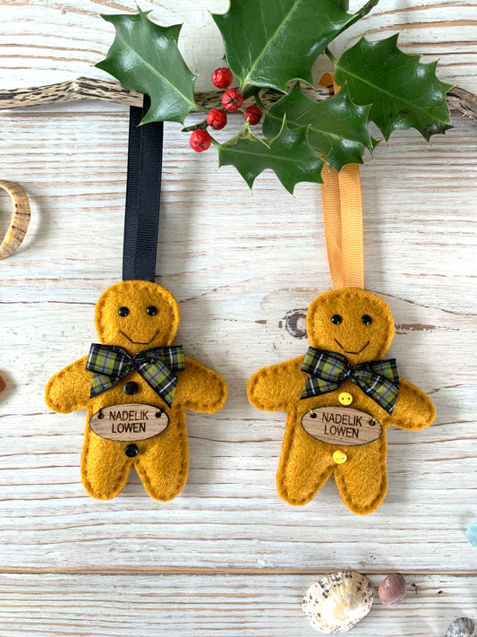 two felt gingerbread men with Cornish tartan neck ribbons and the words Nadelik Lowen